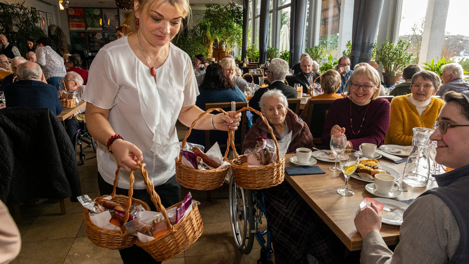 Na zdjęciu kobieta rozdająca koszyki seniorom