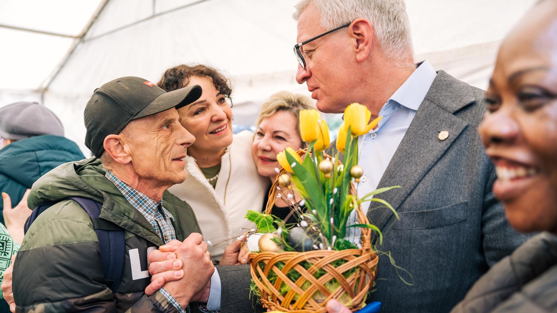 Na zdjęciu prezydent Poznania rozmawiający z mężczyzną, w ręku trzyma żólte tulipany