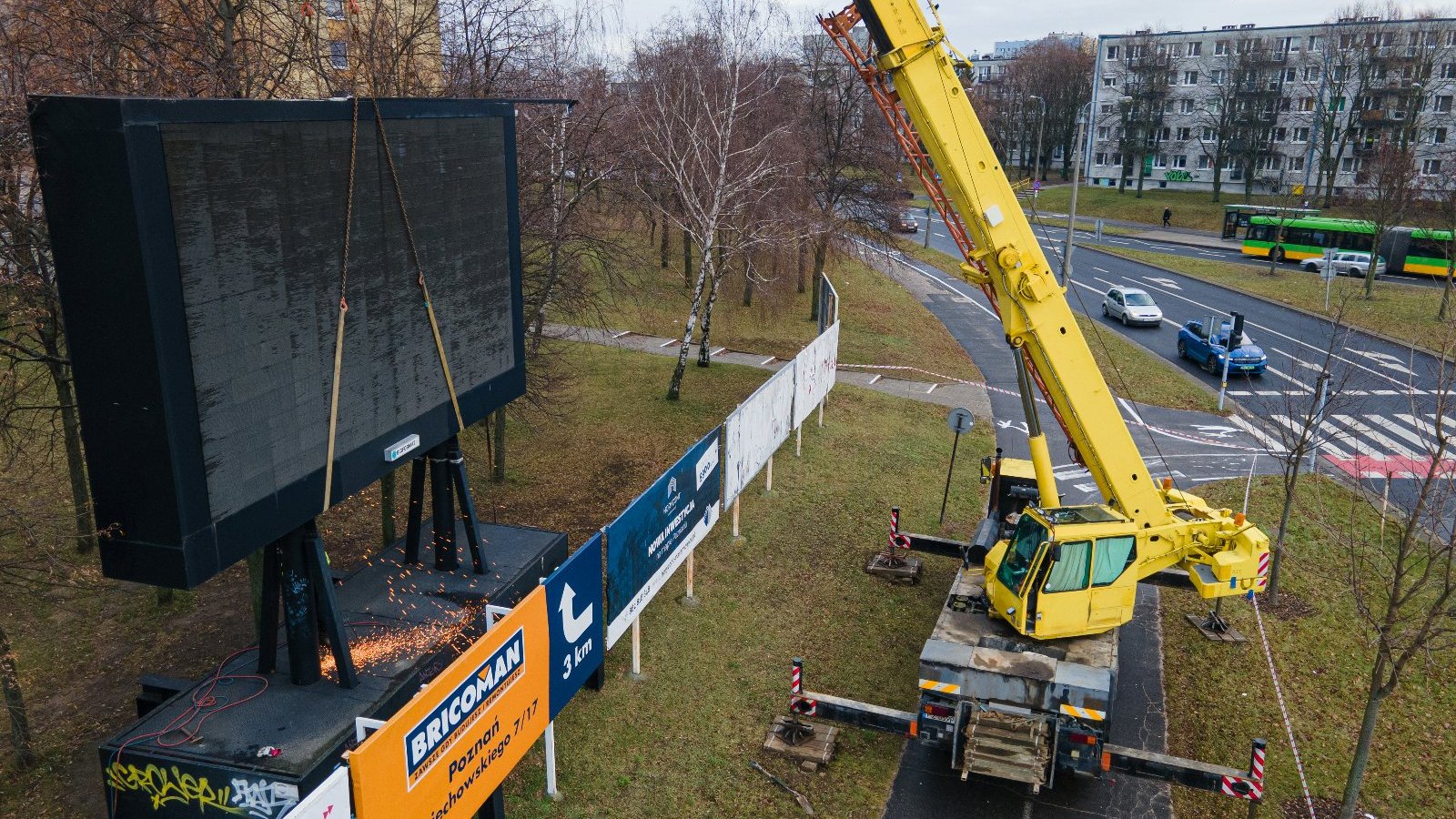 Zdjęcie przedstawia wielkoformatową tablicę LED demontowaną za pomocą dźwigu. - grafika rozmowy