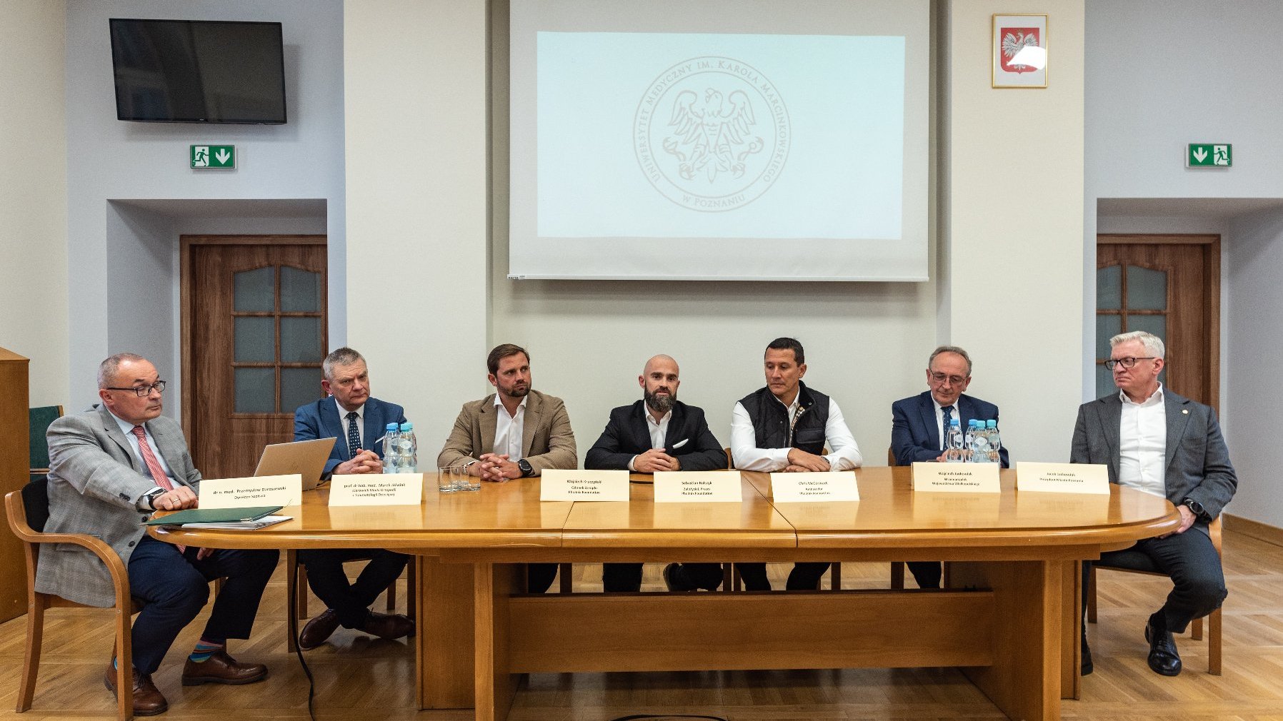 Grupa osób siedzi za stołem konferencyjnym, wśród nich m.in. Jacek Jaśkowiak, prezydent Poznania.