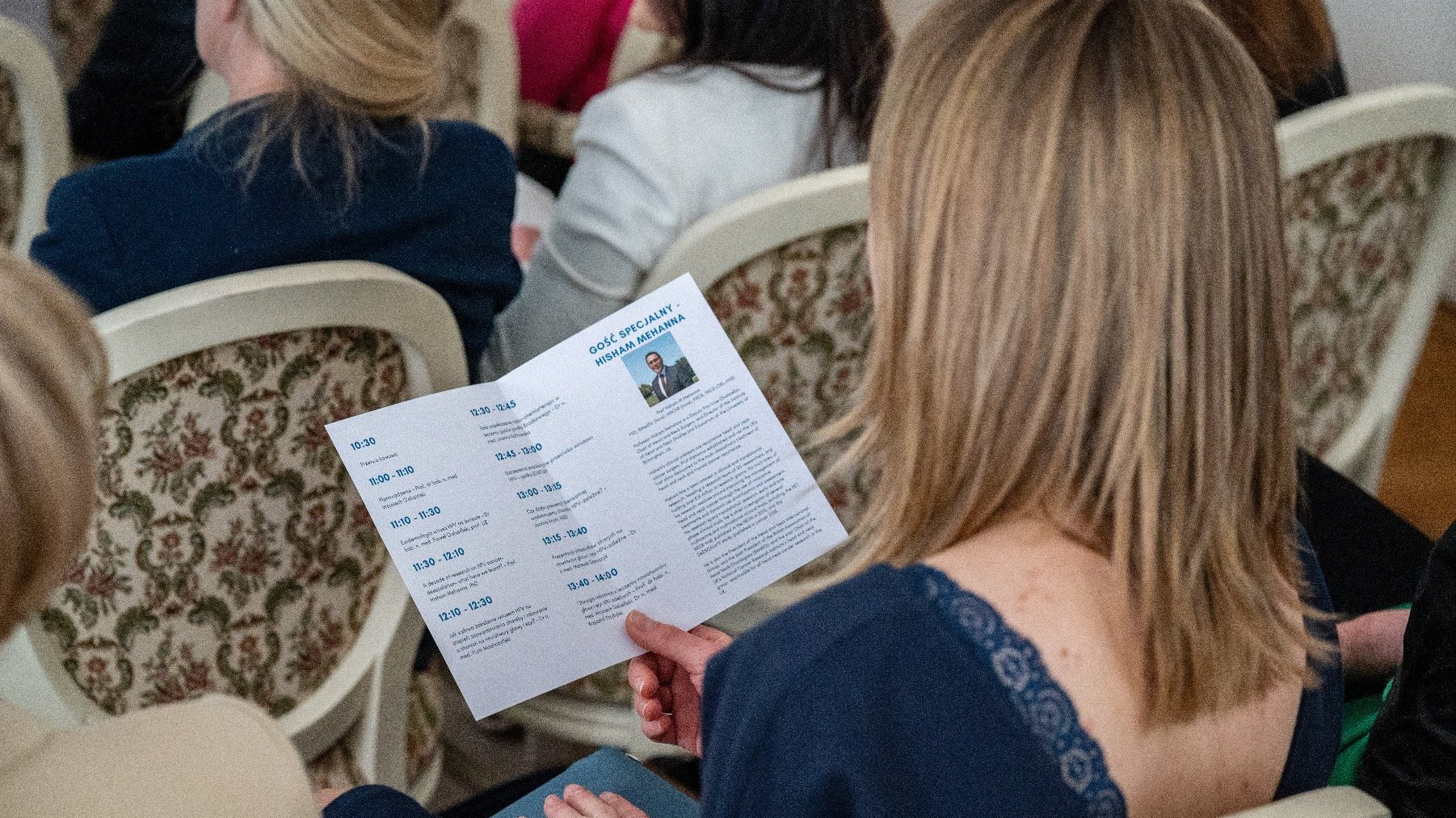 Na zdjęciu słuchaczka konferencji, trzymająca w ręku jej program