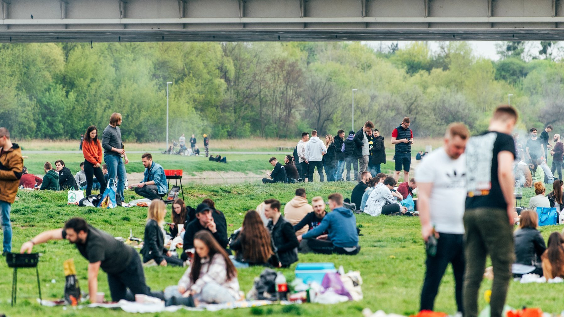 Zdjęcie przedstawia grupę ludzi odpoczywających nad Wartą.