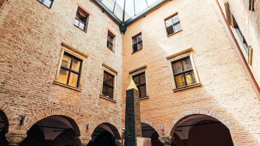 Na zdjęciu dziedziniec muzeum, widać ściany budynków i obelisk w centrum