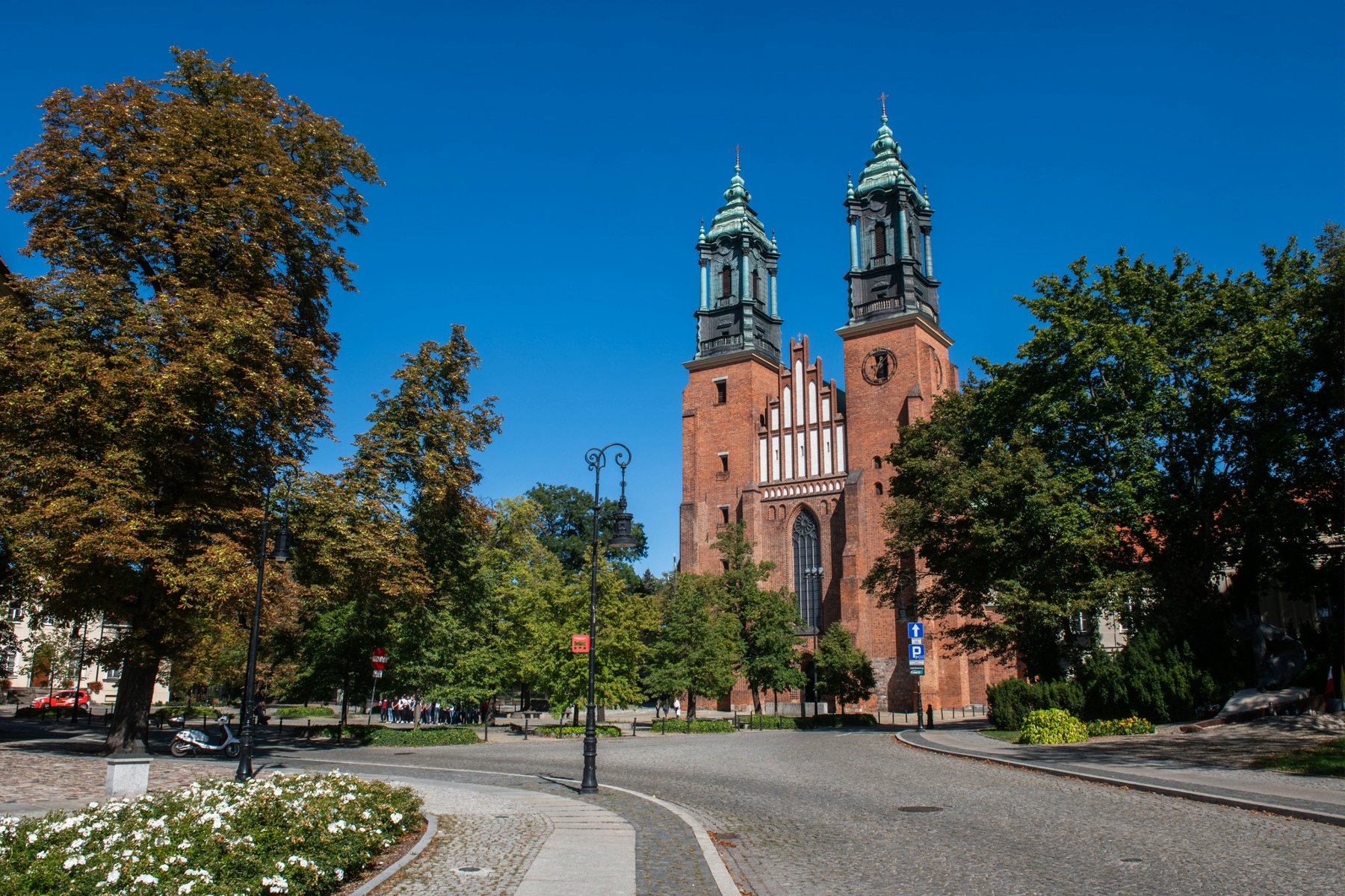 Zdjęcie przedstawia widok na katedrę poznańską, drogę oraz zieleń. - grafika rozmowy