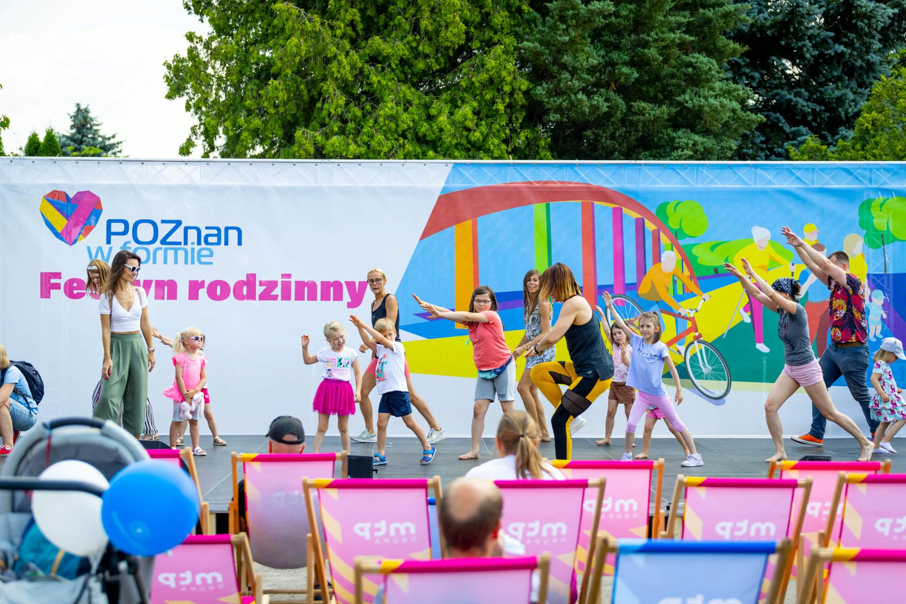 Na zdjęciu grupa ludzi tańczy na scenie na festynie rodzinnym - grafika rozmowy