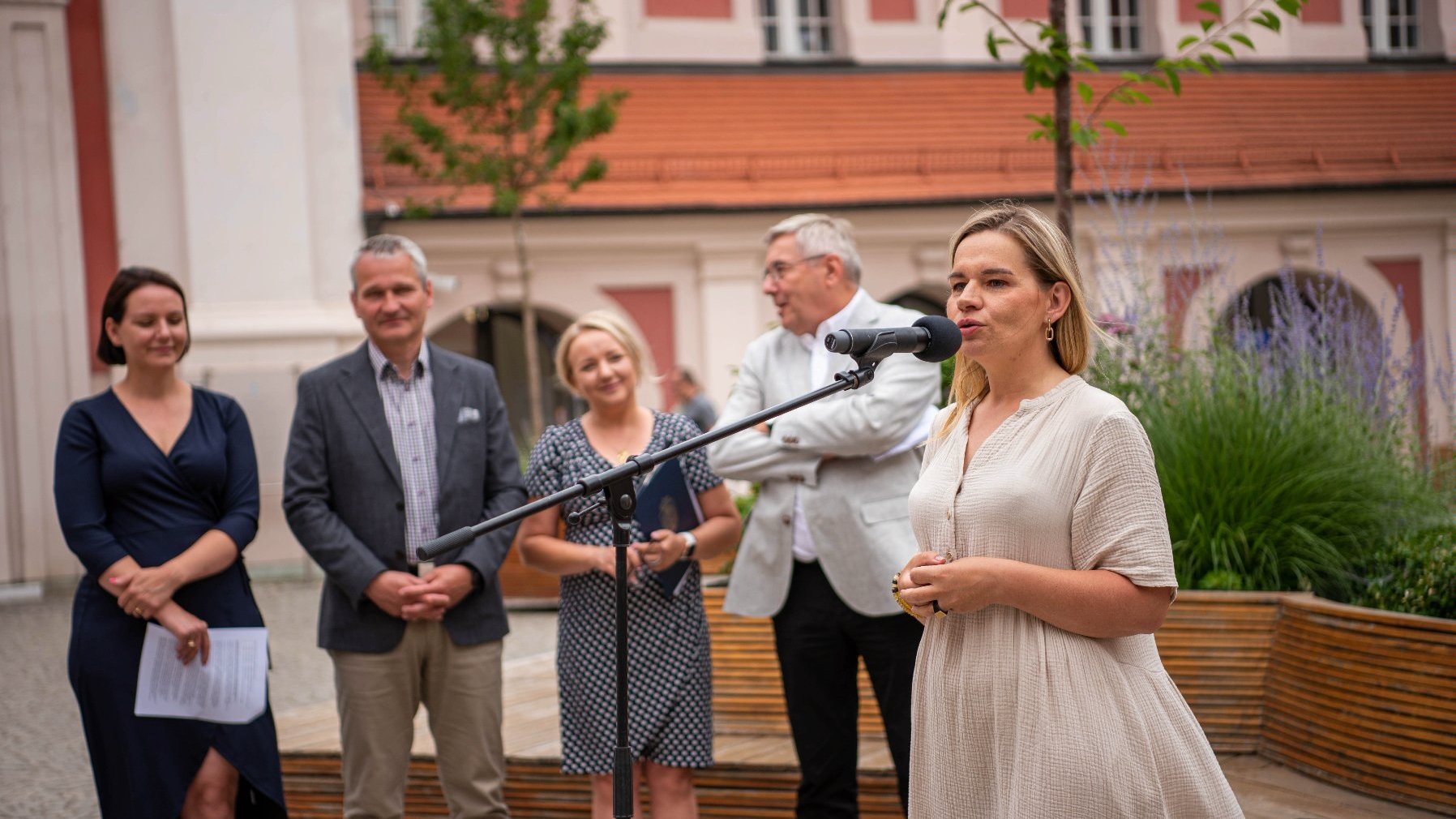 NA zdjęciu uczestnicy konferencji na dziedzińcu urzędu, przy mikrofonie dyrektorka Estrady Poznańskiej