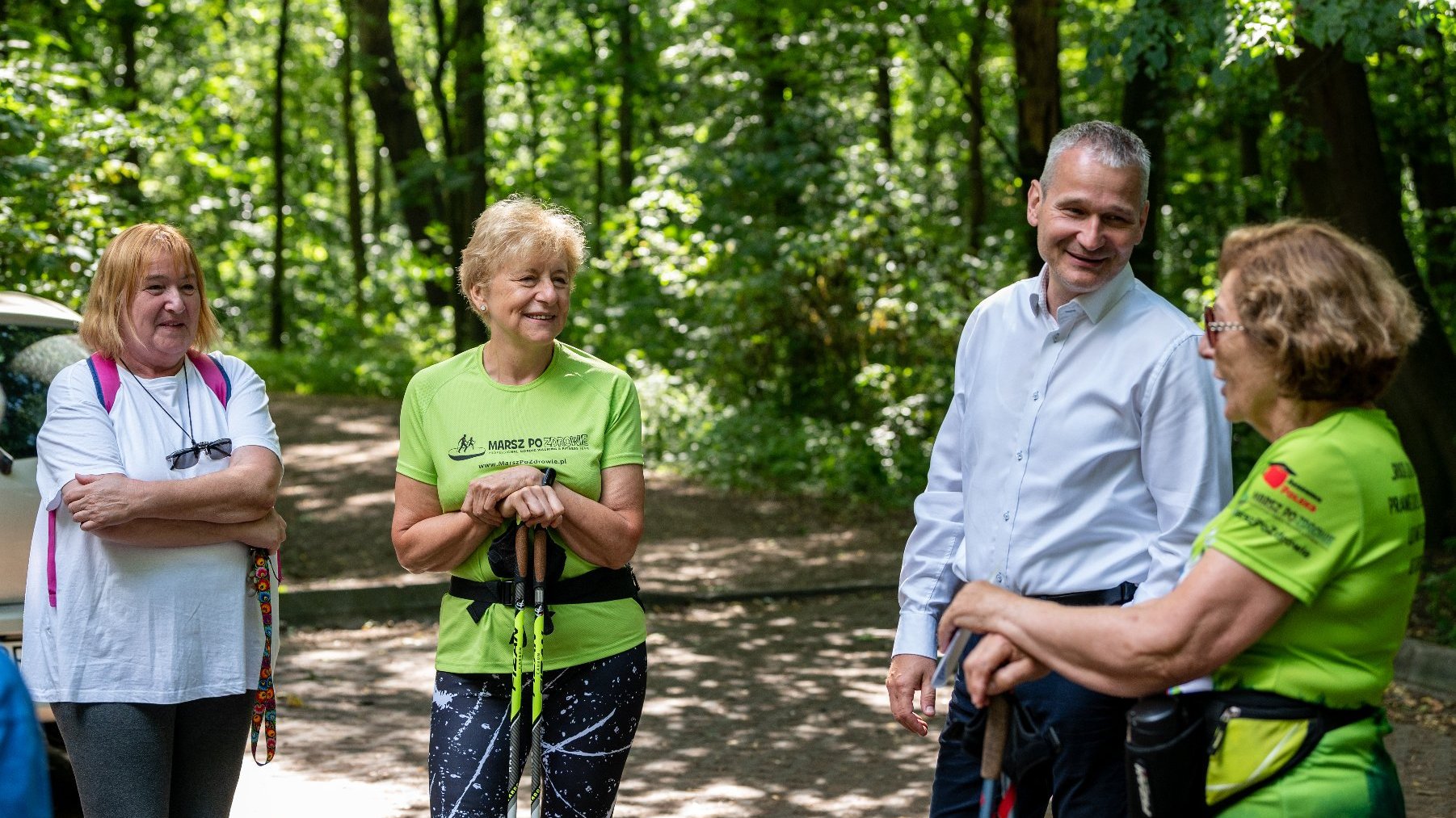 Galeria zdjęć przedstawia grupę seniorów w strojach sportowych z kijkami do nordic walking.