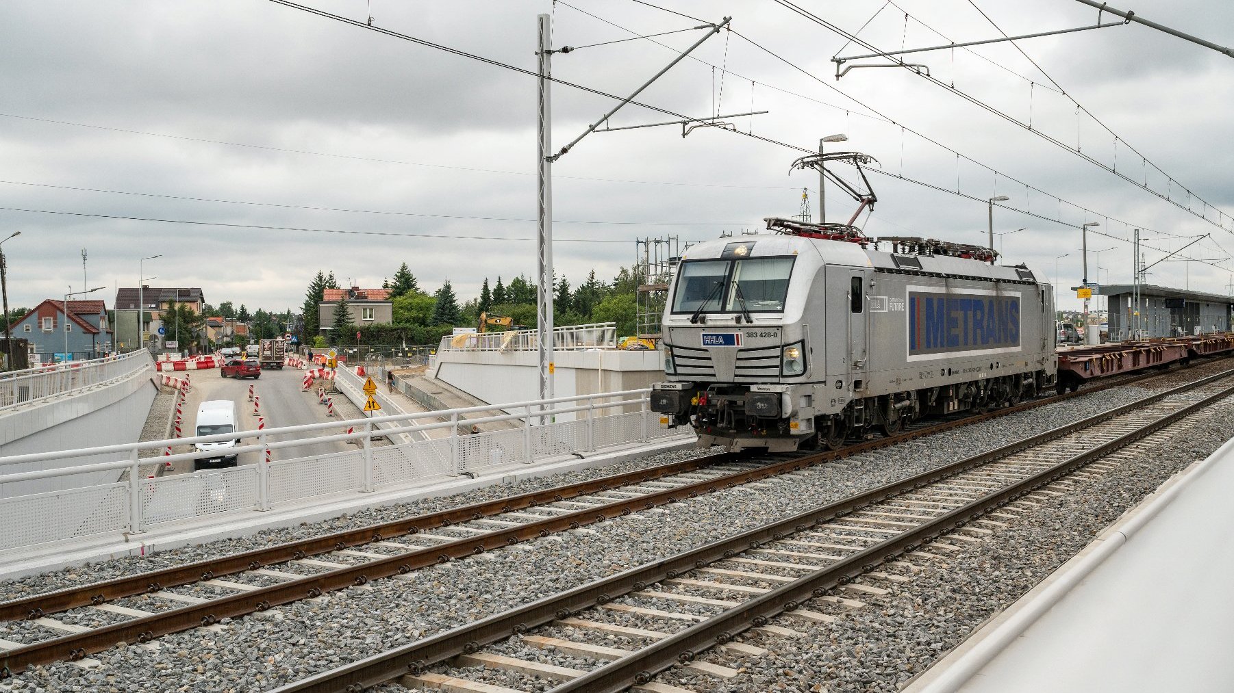 Na zdjęciu pociąg jadący po torach, w tle przejazd pod torami