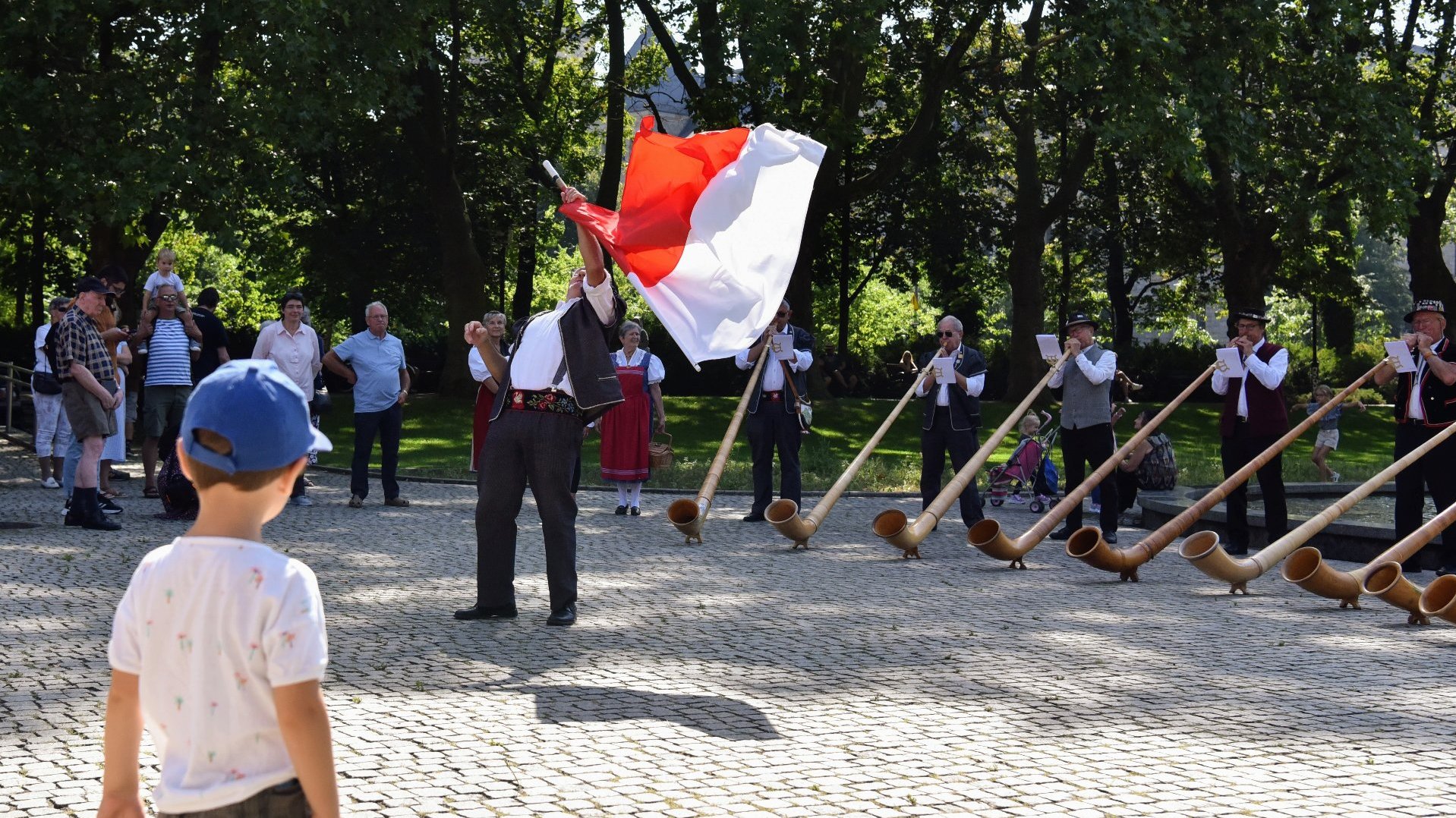 Na zdjęciu muzycy grający na rogach, na pierwszym planie przyglądające się im dziecko