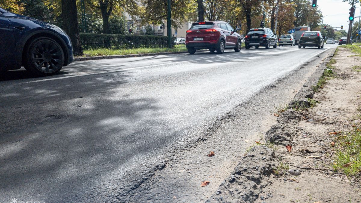 Zniszczona nawierzchnia ul. Reymonta i jadące po niej samochody