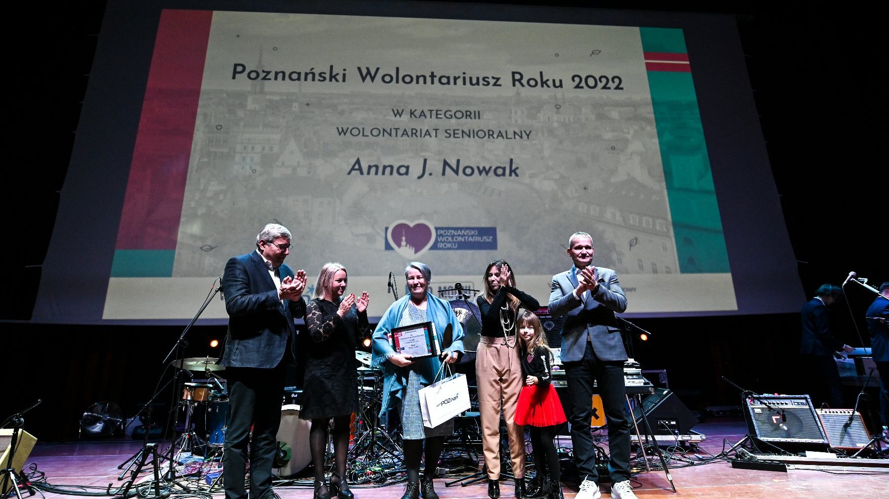 Na zdjęciu widać zwyciężczynię w kategorii Wolontariat Senioralny - Annę J. Nowak. Na scenie nagrodę laureatce wręczają: Grzegorz Ganowicz, przewodniczący rady miasta, Jędrzej Solarski, zastępca prezydenta Poznania, Monika Danelska, miejska radna oraz Magdalena Pietrusik-Adamska, dyrektorka Wydziału Zdrowia i Spraw Społecznych UMP.