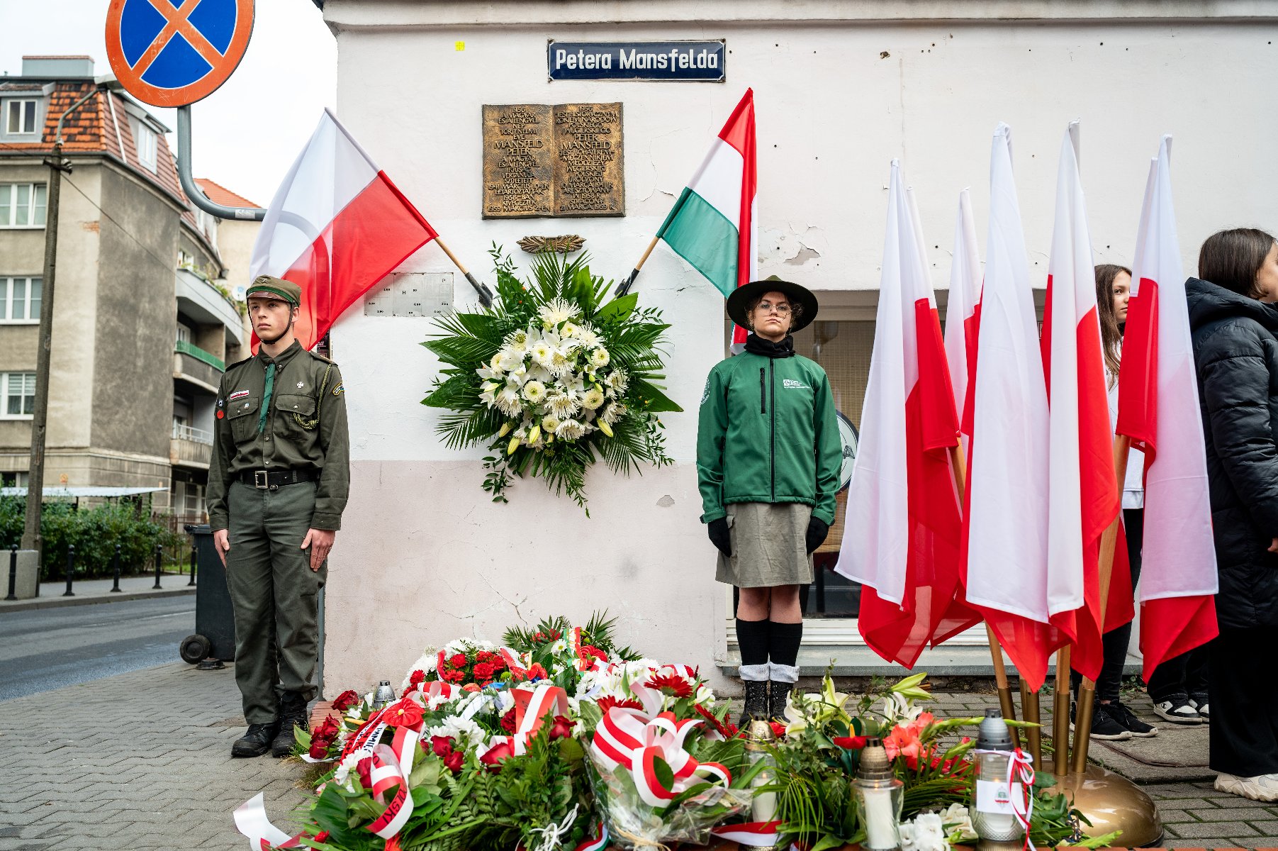 Galeria zdjęć przedstawia obchody rocznicy wybuchu Powstania Węgierskiego, podczas których złożono kwiaty pod tablicami upamiętniającymi Pétera Mansfelda i Romka Strzałkowskiego. - grafika rozmowy