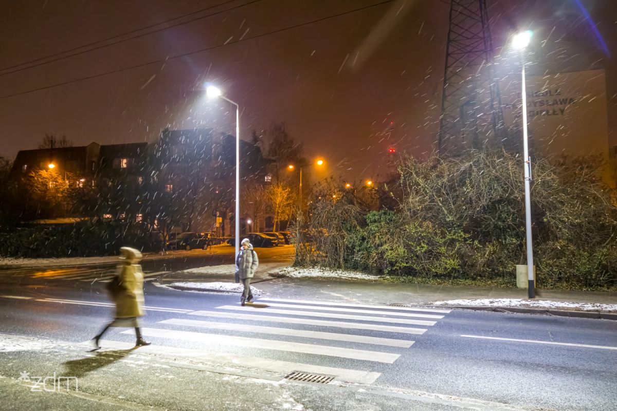 Galeria zdjęć przedstawia oświetlone przejście dla pieszych. - grafika rozmowy