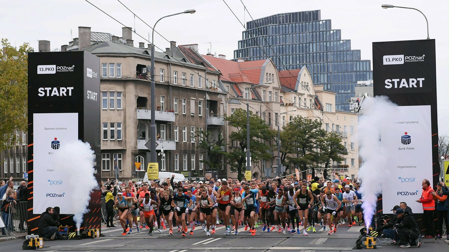 Zdjęcie przedstawia grupę startujących do biegu sportowców. W tle widać kamienice i biurowiec Bałtyk. - grafika rozmowy