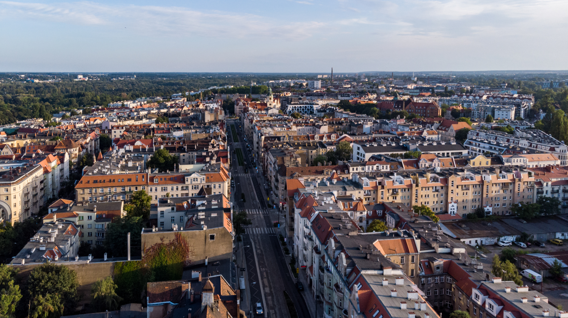 Zdjęcie przedstawia panoramę Poznania. W środku kadru widać jezdnię i chodniki otoczone gęstą zabudową. - grafika rozmowy