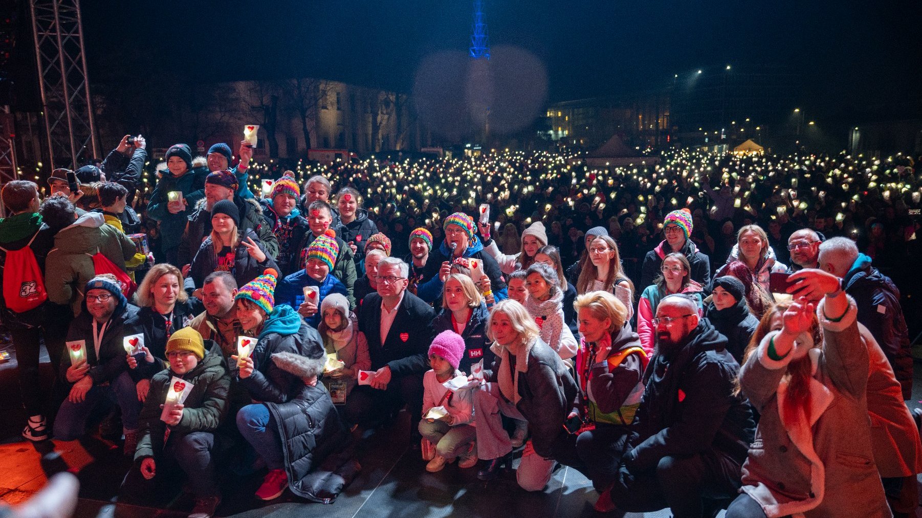 Rozświetlony tysiącami latarek plac PKW na terenie MTP i osoby na scenie