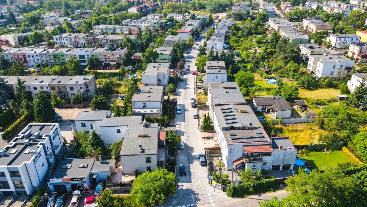 Zdjęcie przedstawia widok na budynki jednorodzinne, zieleń i drogi z lotu ptaka. - grafika rozmowy