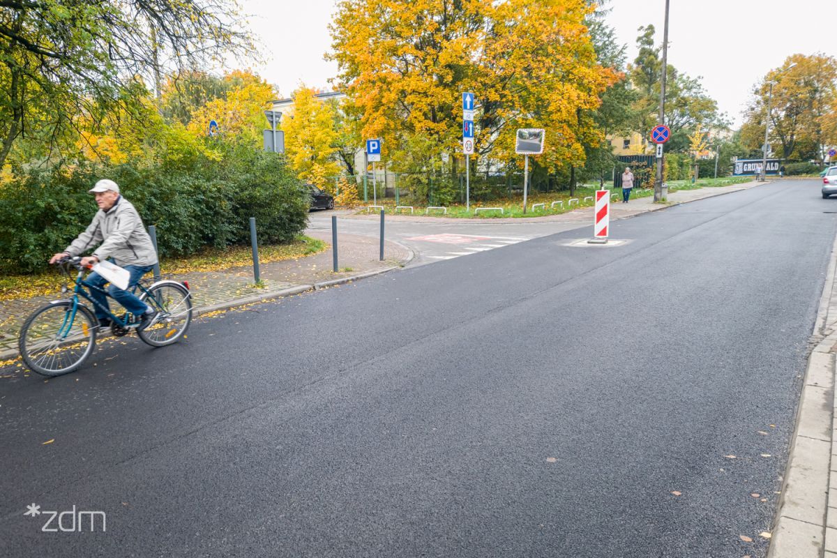 Zdjęcie przedstawia jezdnię, po której porusza się rowerzysta. W tle drzewa. - grafika rozmowy