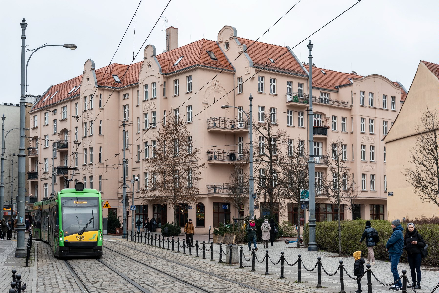 na zdjęciu kamienica ZKZL przy ul. Wrocławskiej, widać budynek, przejeżdżający obok niego tramwaj i przechodniów - grafika rozmowy