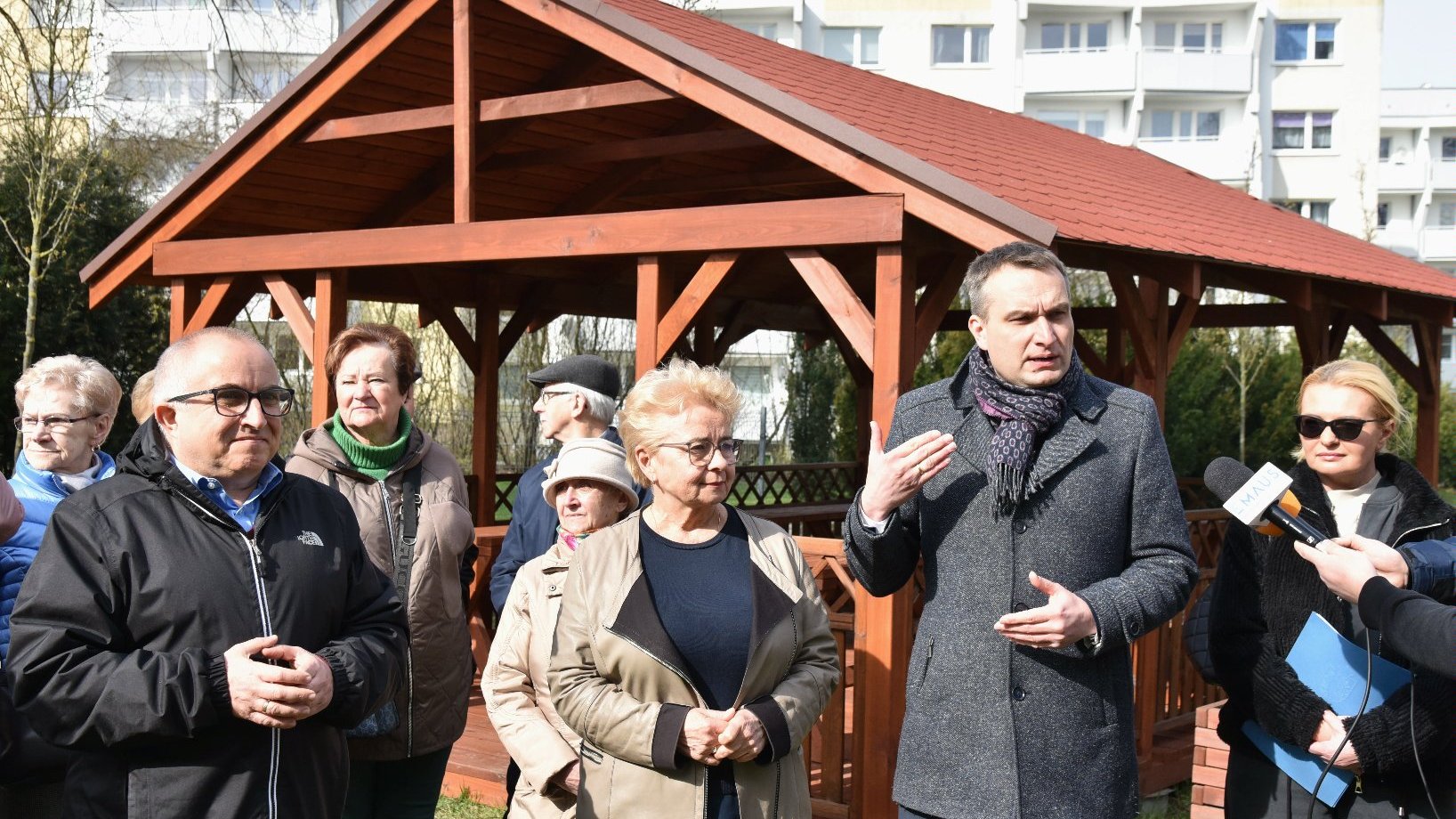 Zdjęcie przedstawia uczestników konferencji na tle altany.