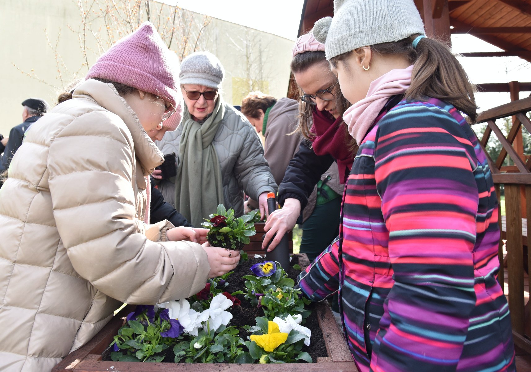 Zdjęcie przedstawia dzieci i dorosłych sadzących rosliny. - grafika rozmowy