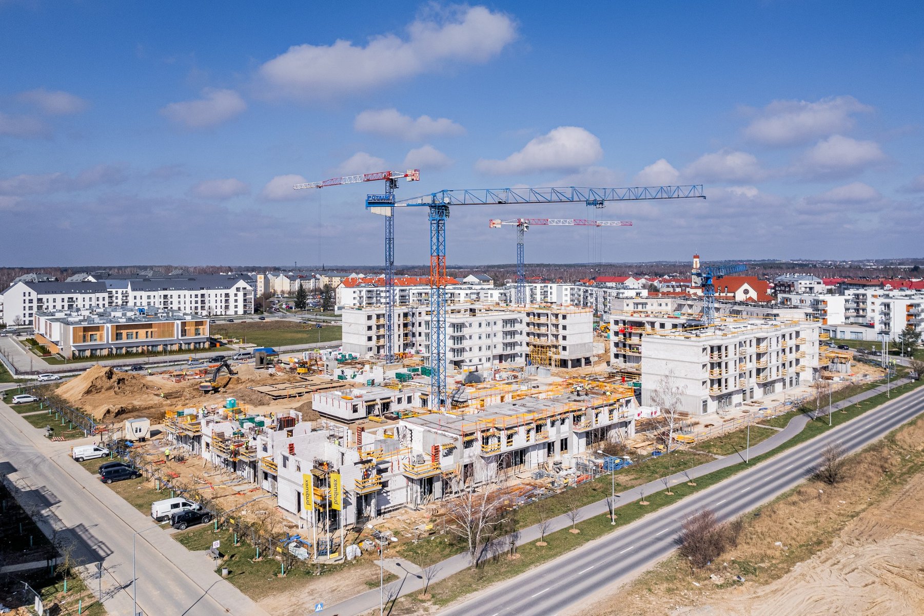 Zdjęcie z lotu ptaka przedstawia plac budowy, nad którym górują dzwigi. - grafika rozmowy