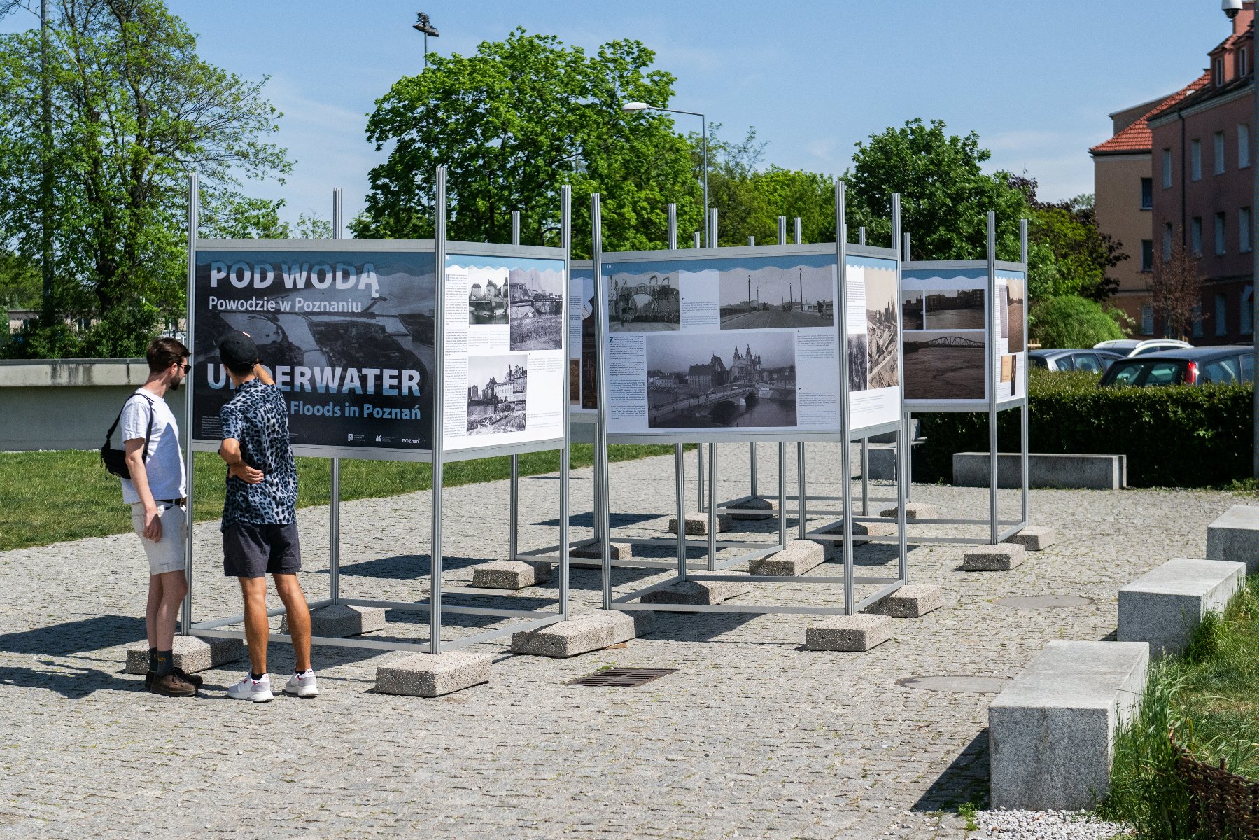 Galeria zdjęć przedstawia ludzi oglądających wystawę "Pod wodą. Powodzie w Poznaniu". - grafika rozmowy