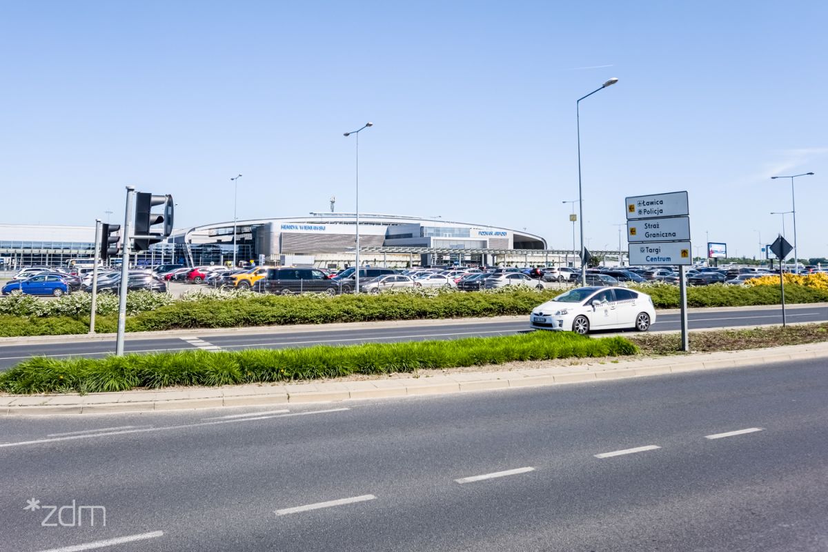 Zdjęcie od ul. Bukowskiej pokazujące parking, a w tle budynek lotniska - grafika rozmowy