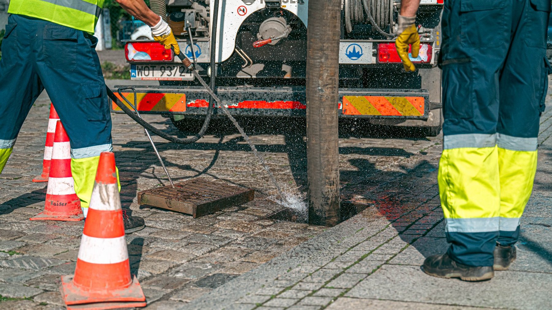 Zdjęcie przedstawia ludzi podczas czyszczenia studzienki.