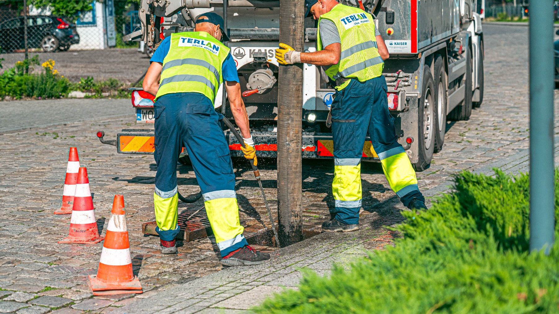 Zdjęcie przedstawia ludzi podczas czyszczenia studzienki.