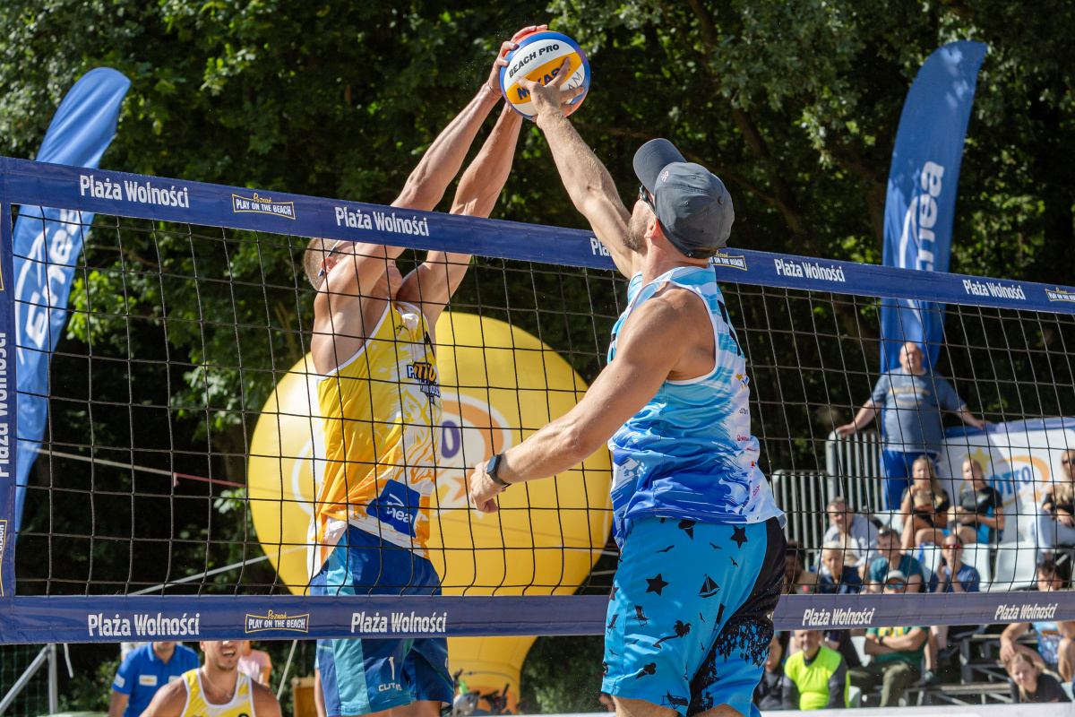 Zdjęcie siatkarzy plażowych wyskakujących do piłki nad siatką - grafika rozmowy