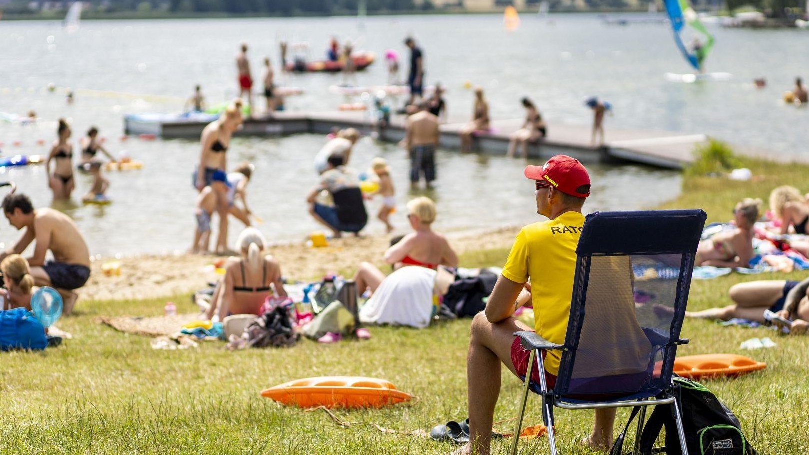 Zdjęcie przedstawia ratownika i tłum ludzi na plaży.