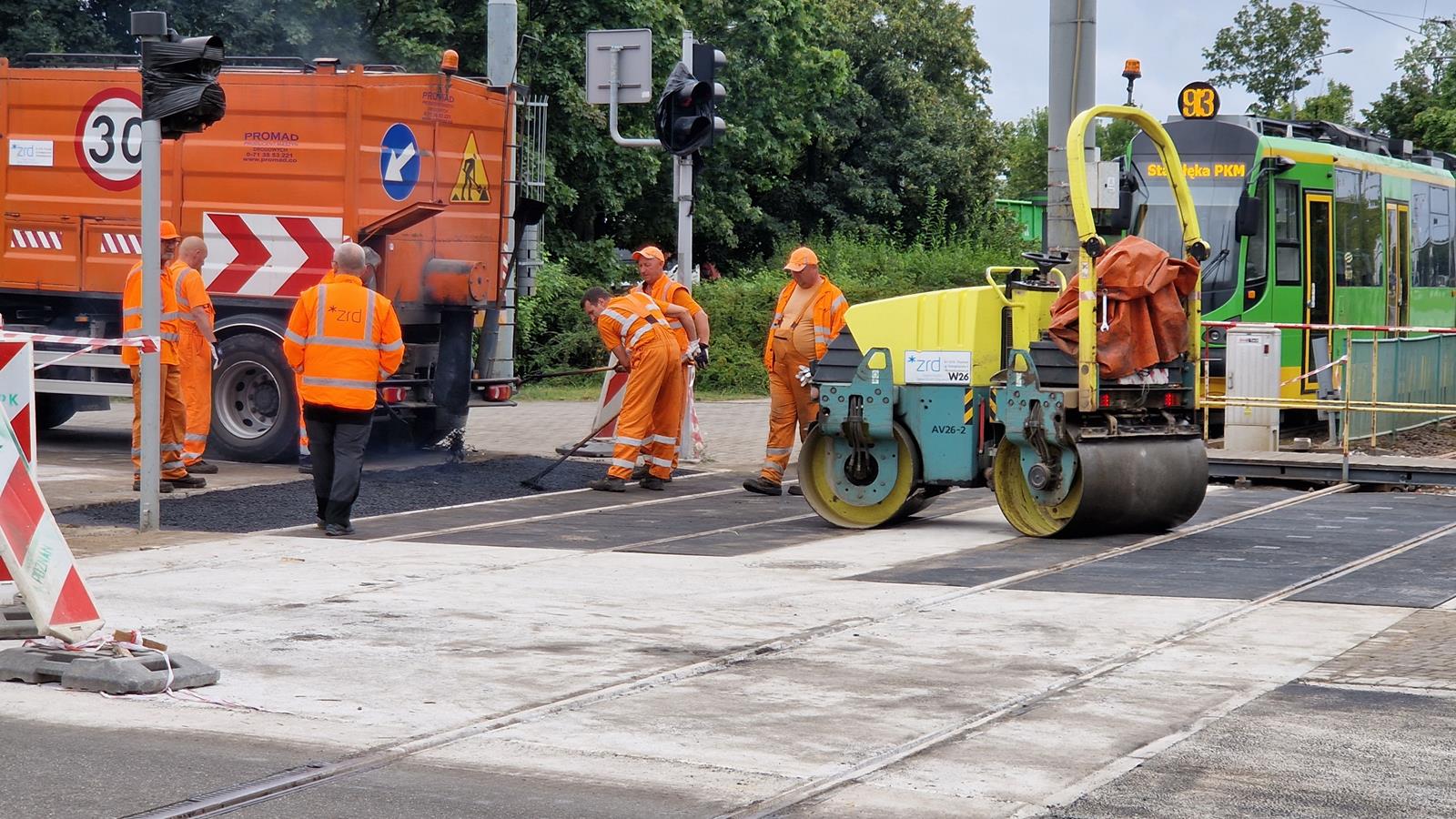 Na zdjęciu na pierwszym planie widoczna nowa nawierzchnia, w tle pracownicy - grafika rozmowy