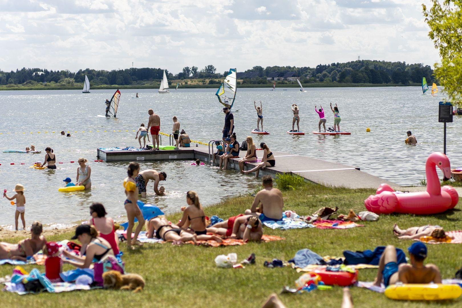 Zdjęcie przedstawia ludzi na plaży i w wodzie. - grafika rozmowy