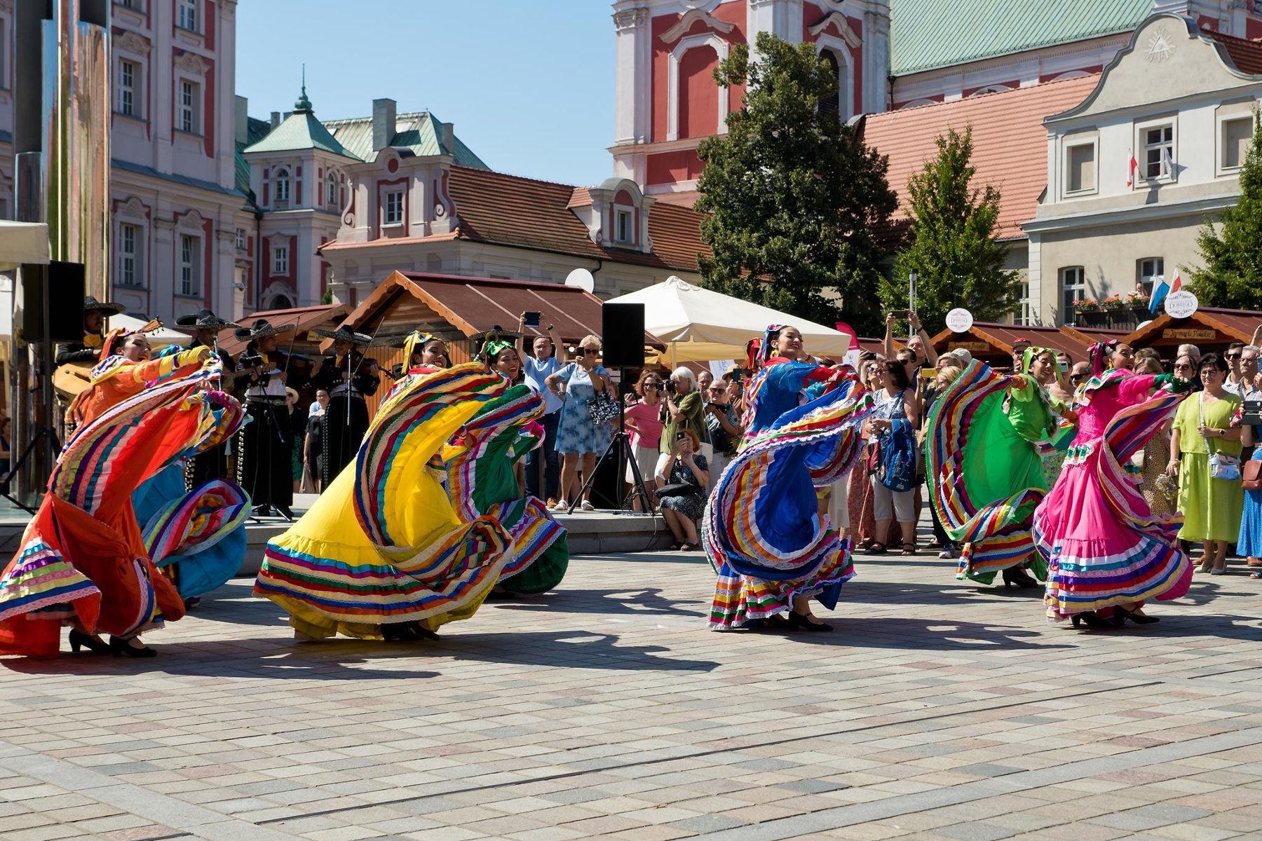 Zdjęcie z zeszłorocznej edycji Festiwalu dobrego Smaku. Na pierwszym planie tańczące kobiety w kolorowych strojach - grafika rozmowy