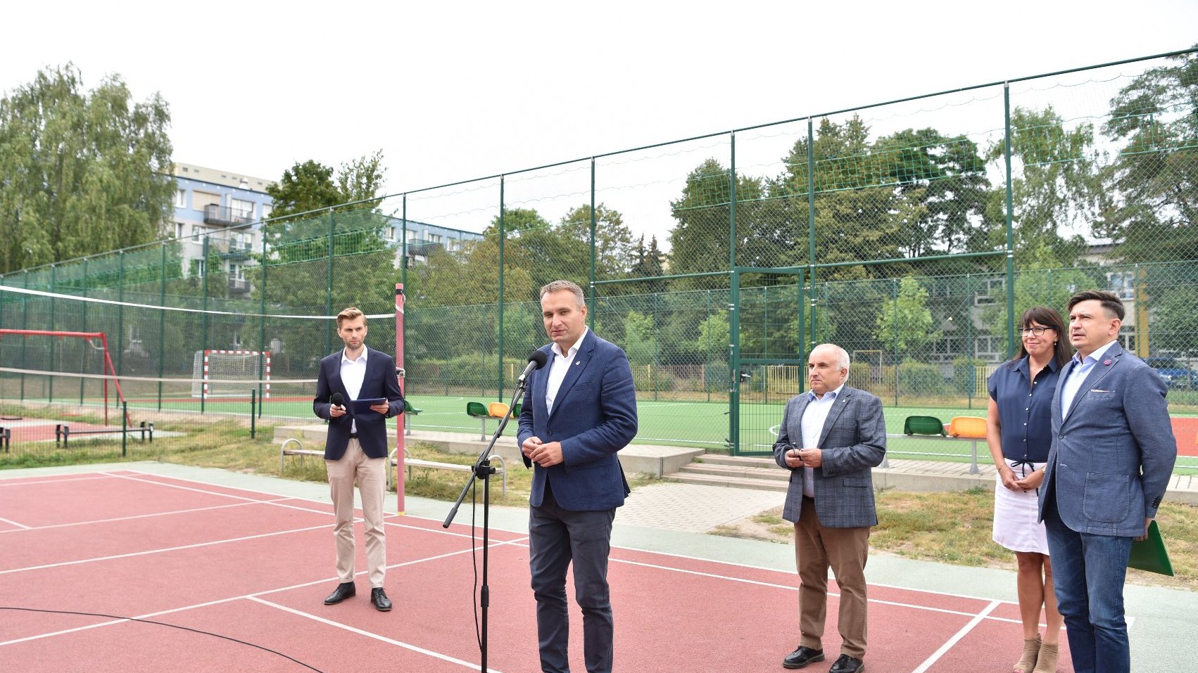 Zdjęcie przedstawia osoby biorące udział w konferencji prasowej na boisku.