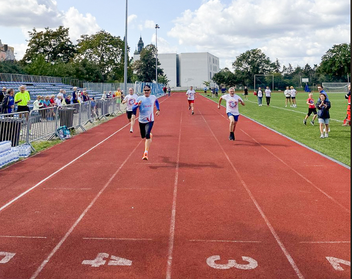 Na zdjęciu seniorzy wbiegający na metę na stadionie lekkoatletycznym - grafika rozmowy