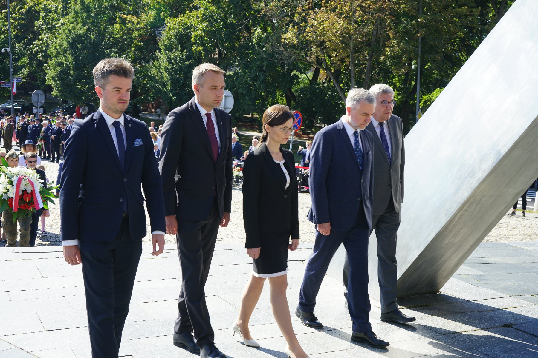 Na zdjeciu przedstawiciele władz rządowych i samorządowych podczas składania wiązanki kwiatów - grafika rozmowy