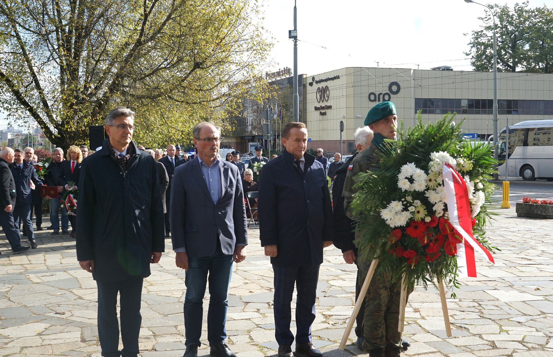 Na zdjęciu czterej mężczyźni składający wiązankę - grafika rozmowy