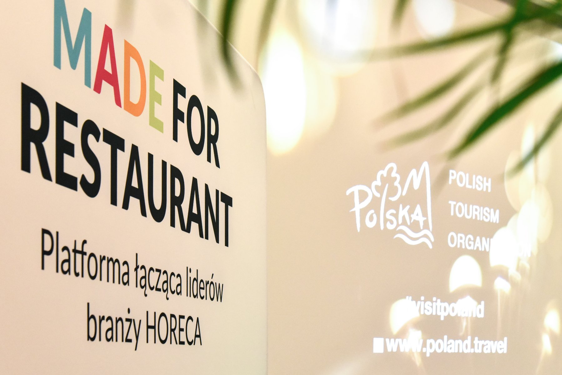 Zdjęcie przedstawia plakat konferencji "Made for Restaurant". Znajdują się na niej kolorowe literki, które stanowią słowo "made". W tle widoczny jest ekran projektora - grafika rozmowy