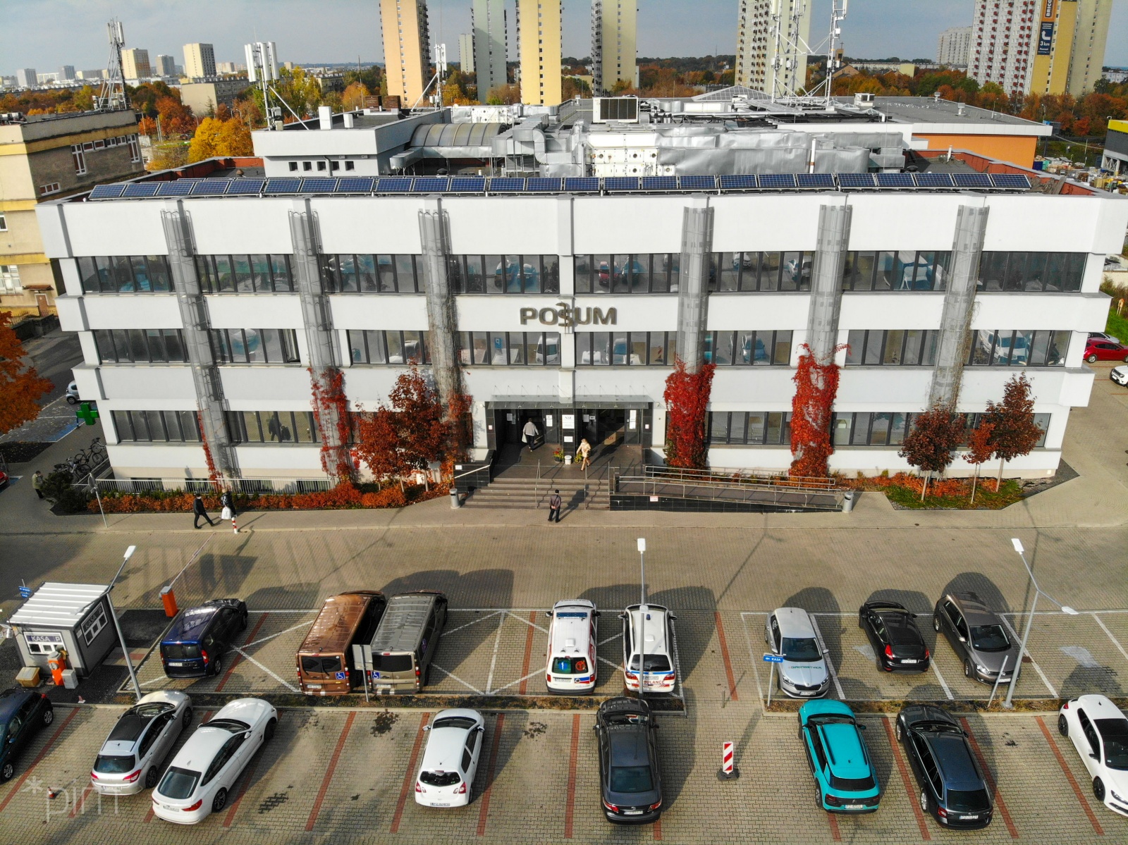 Na zdjęciu budynek POSUM widziany z lotu ptaka, przed nim widać parking z samochodami - grafika rozmowy