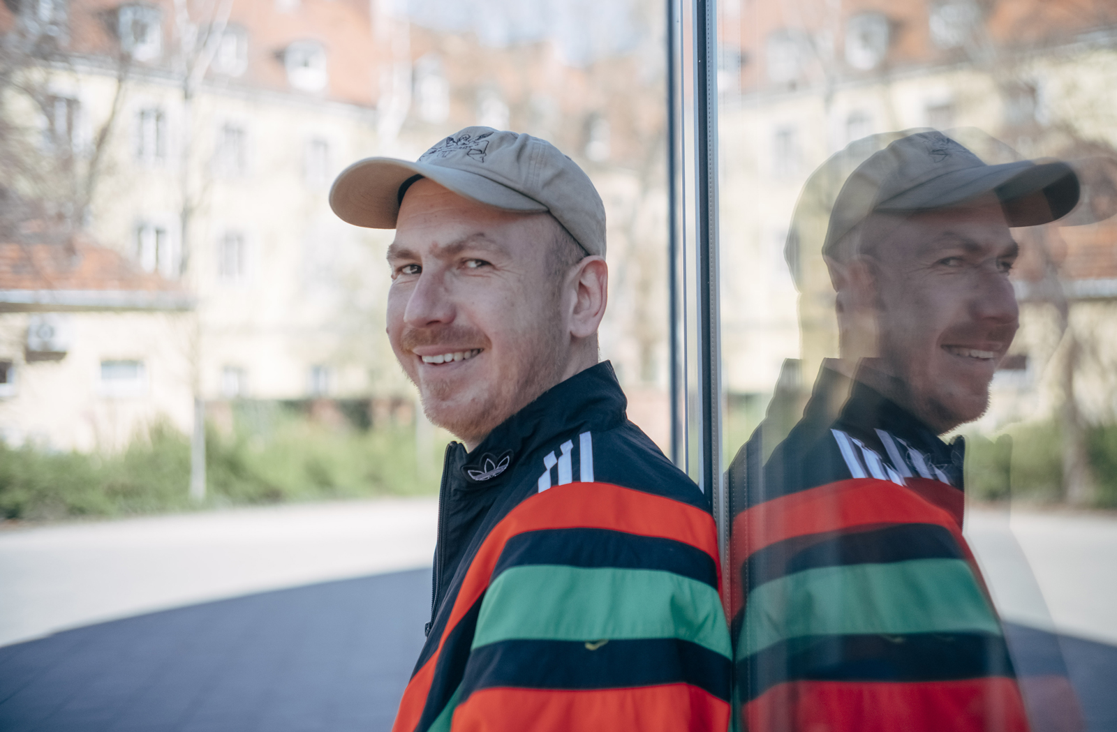 Uśmiechnięty mężczyzna w czapce z daszkiem i sportowej kurtce - grafika rozmowy