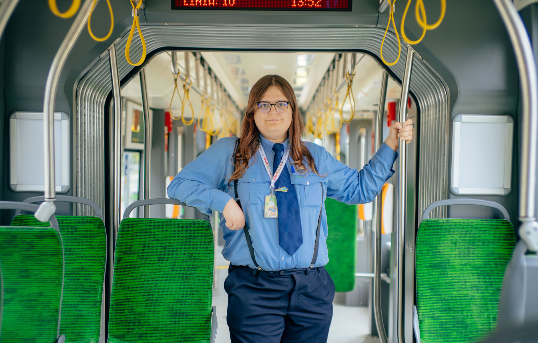 młoda kobieta w stroju motorniczego stoi w tramwaju - grafika rozmowy