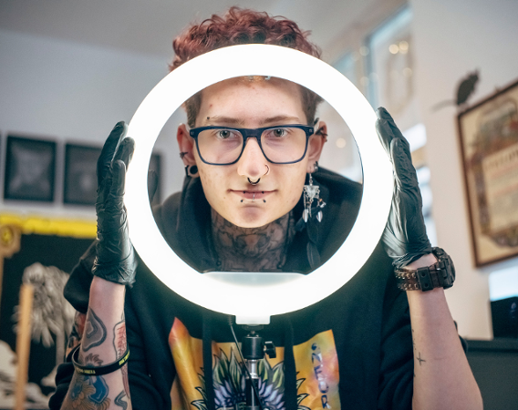 young man wearing glasses holding a circular lamp