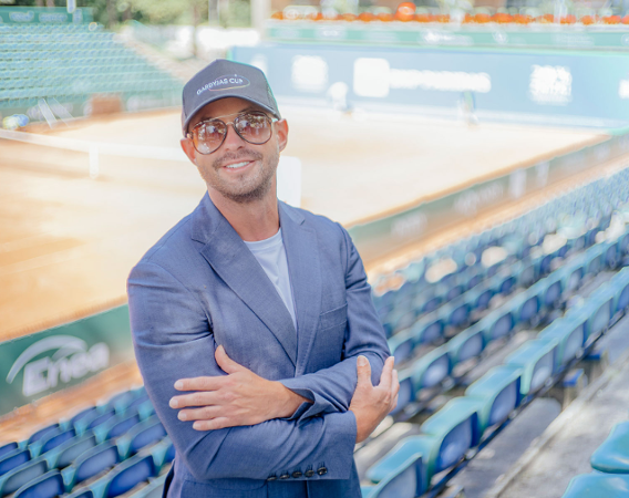 Mężczyzna w czapce z daszkiem i okularach na tle hali sportowej