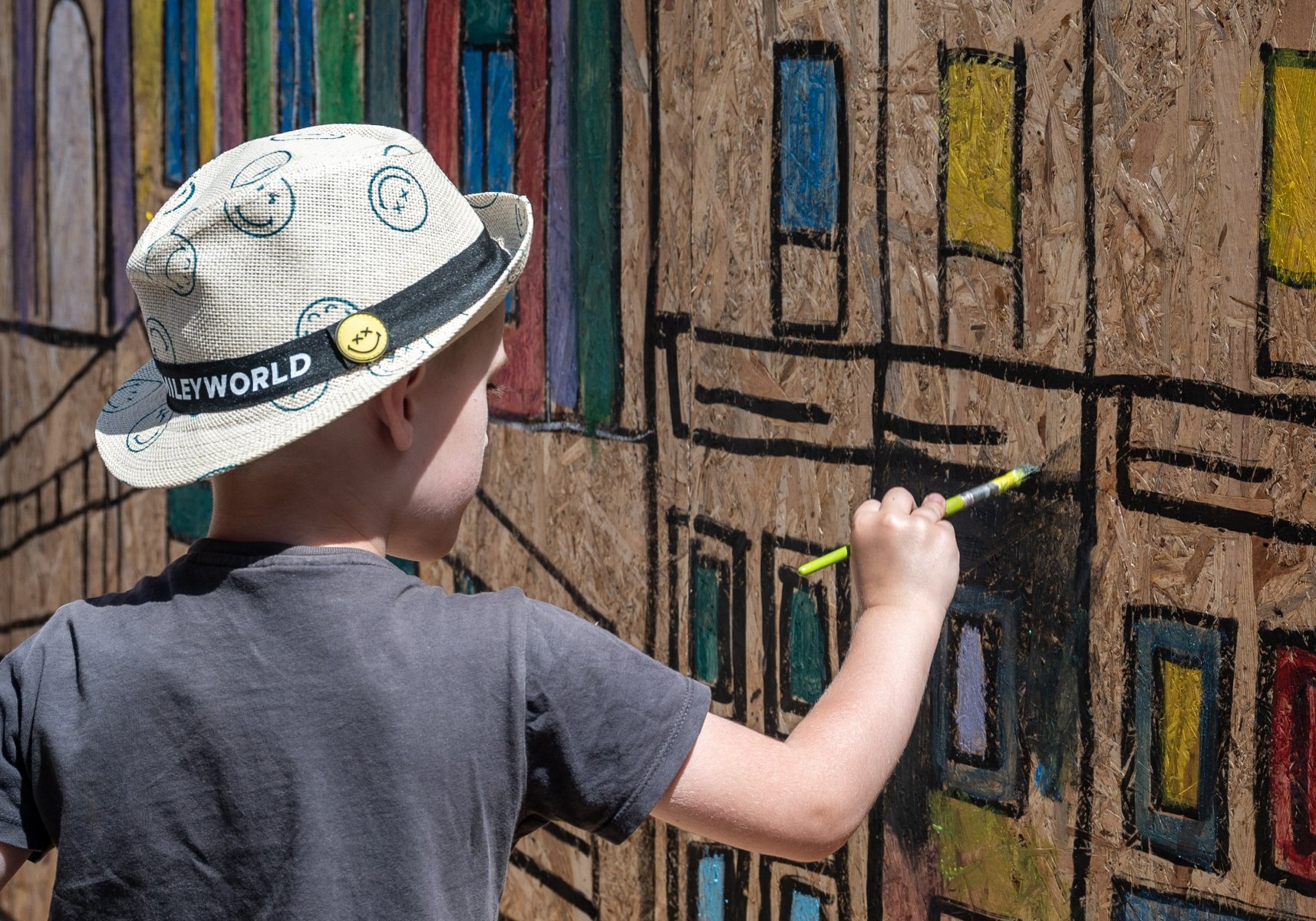 Na zdjęciu dziecko malujące poznańskie budynki na dużej dykcie