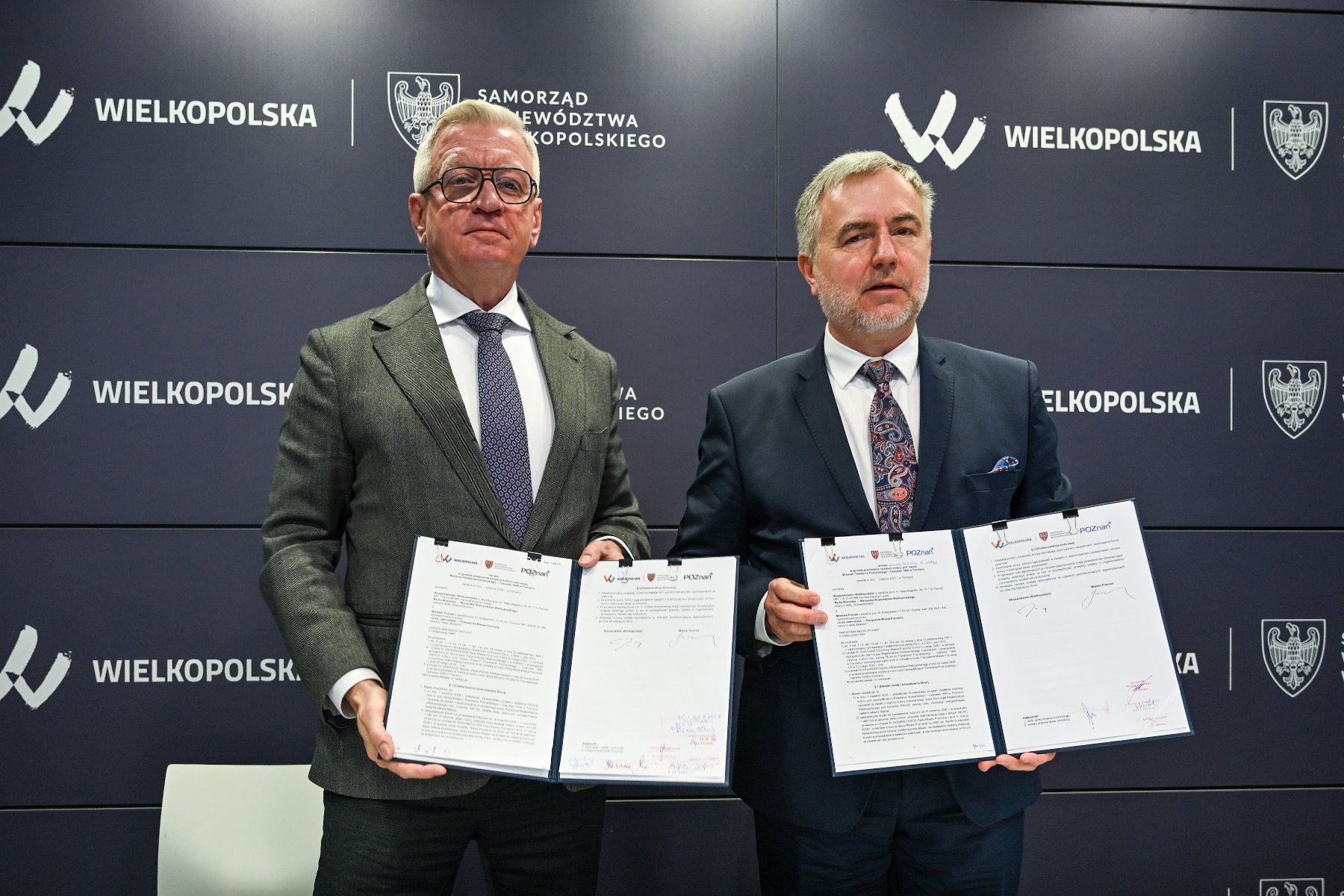 Zdjęcie przedstawia dwóch mężczyzn - prezydenta i marszałka - pozujących do zdjęcia. W rękach trzymają podpisane umowy.