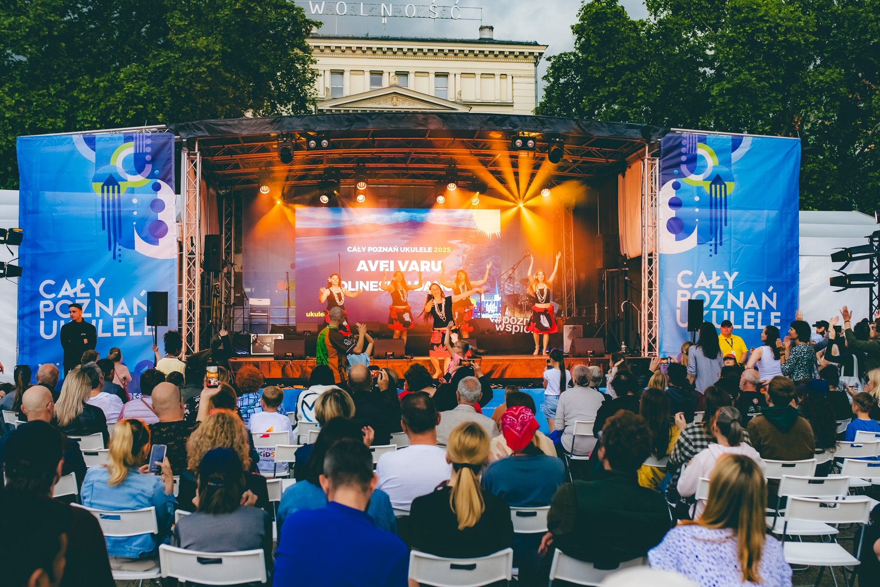 Zdjęcie przedstawia dziewczynę na scenie grającą na ukulele.